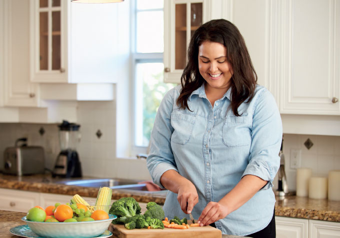 A female chopping vegetables in the kitchen