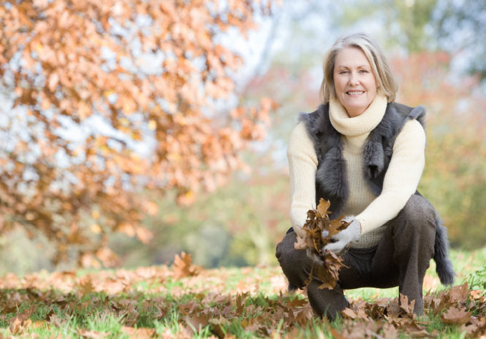 A mature lady gathering fallen tree leaves
