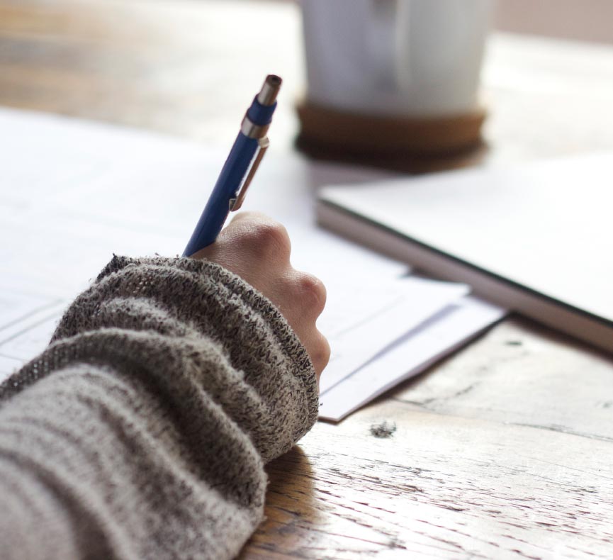 A hand holding a pen and making notes